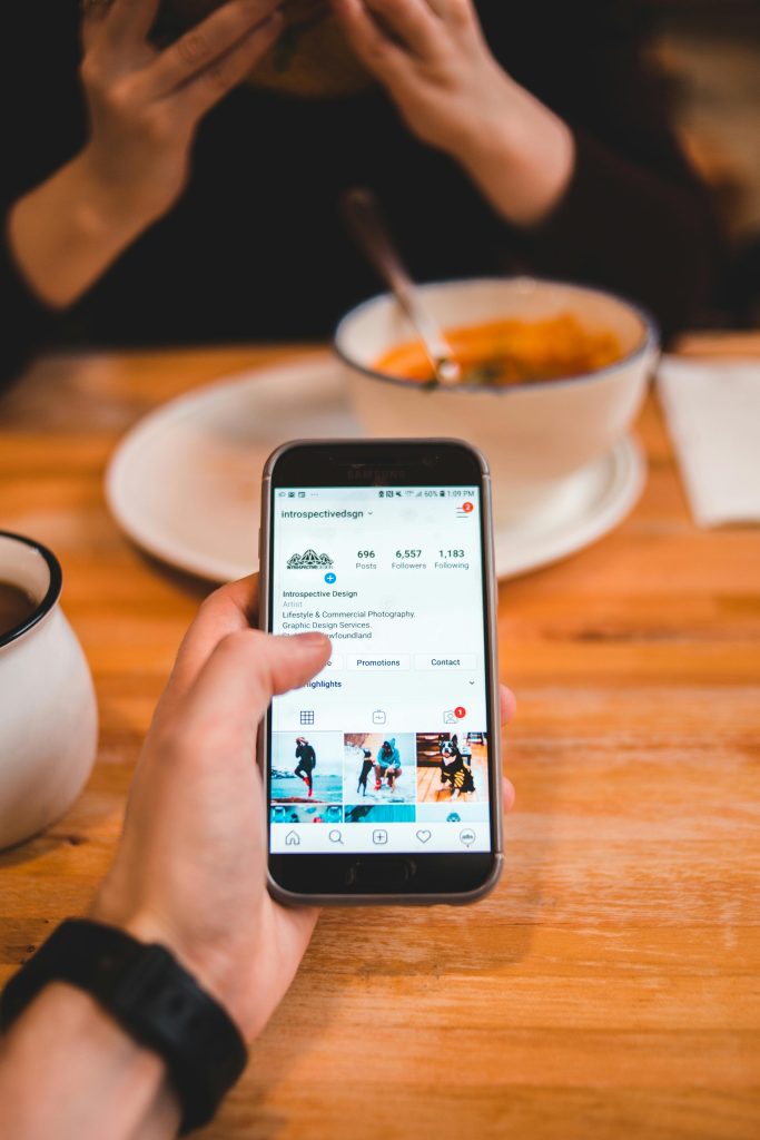 pexels-photo-4062294-4062294 From above of crop anonymous male browsing social media on mobile phone while sitting at wooden table with woman eating bright soup in restaurant